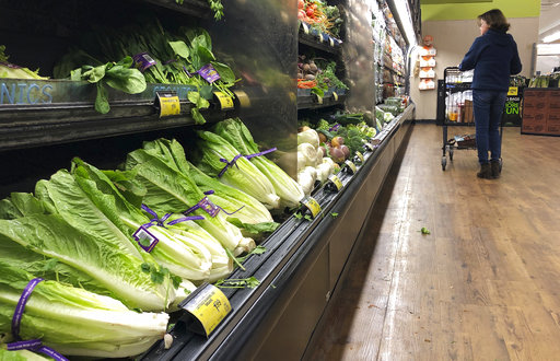 FILE - In this Nov. 20, 2018 file photo, romaine lettuce sits on the shelves as a shopper walks through the produce area of an Albertsons market in Simi Valley, Calif.  After repeated food poisoning outbreaks linked to romaine lettuce, the produce industry is confronting the failure of its own safety measures in preventing contaminations. The latest outbreak underscores the challenge of eliminating risk for vegetables grown in open fields and eaten raw. It also highlights the role of nearby cattle operations and the delay of stricter federal food safety regulations.  (AP Photo/Mark J. Terrill, File)