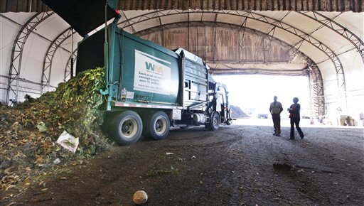 In this Tuesday, Sept. 20, 2011 photo, visitors watch as a truck dumps compost materials inside a receiving area at the Cedar Grove processing facility in Everett, Wash. The city of Seattle began requiring residents in 2009 to recycle their food scraps along with weekly yard waste pickup and the results have been impressive: in 2010, the citys contractor kept 90,000 tons of Seattleites banana peels, chicken bones and weeds out of landfills and converted that waste into rich compost prized in gardens. But the company processing that green waste has come under fire by citizens and others who complain of a pungent stench emanating from its two facilities located outside of Seattle. (AP Photo/Elaine Thompson)