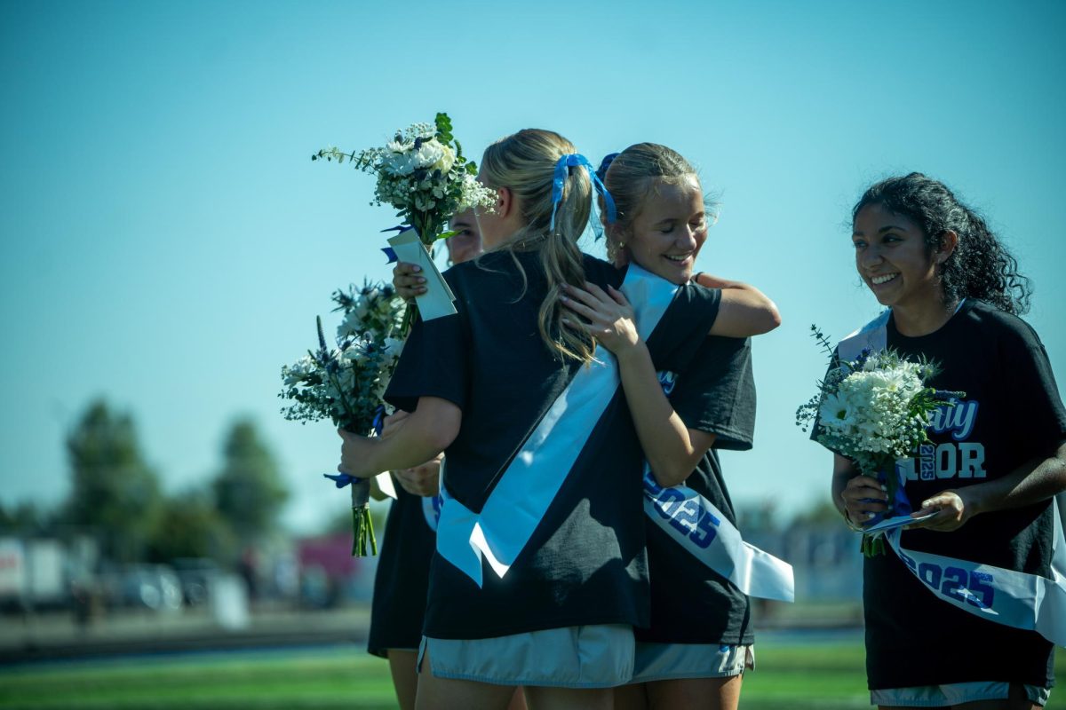 Senior Kate Heym hugs senior Meredith Williams after accepting her flowers.