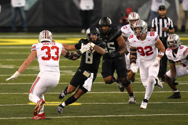 EUGENE, OREGON - OCTOBER 12: Dillon Gabriel #8 of the Oregon Ducks runs the ball against Jack Sawyer #33 and Caden Curry #92 of the Ohio State Buckeyes during the third quarter at Autzen Stadium on October 12, 2024 in Eugene, Oregon. (Photo by Ali Gradischer/Getty Images)