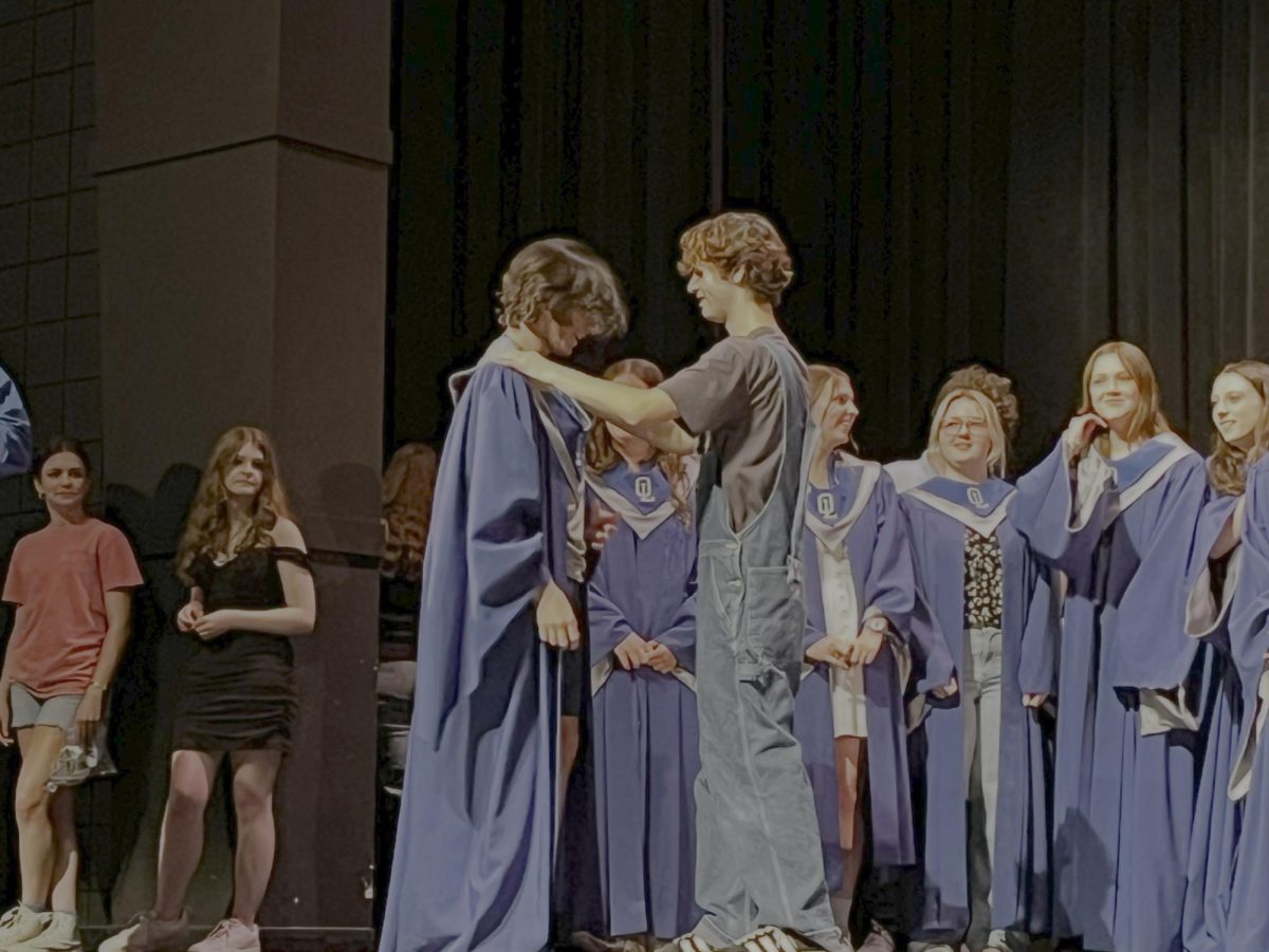Grant Hatzigeorgiou '28 stands patiently as he receives his robe and is inducted into Varsity Chorale. Mikey Tripodi '25 gave him the robe to induct him. “All the soloists did good and watching some of the seniors’ last moments was very special” Hatzigeorgiou said. 